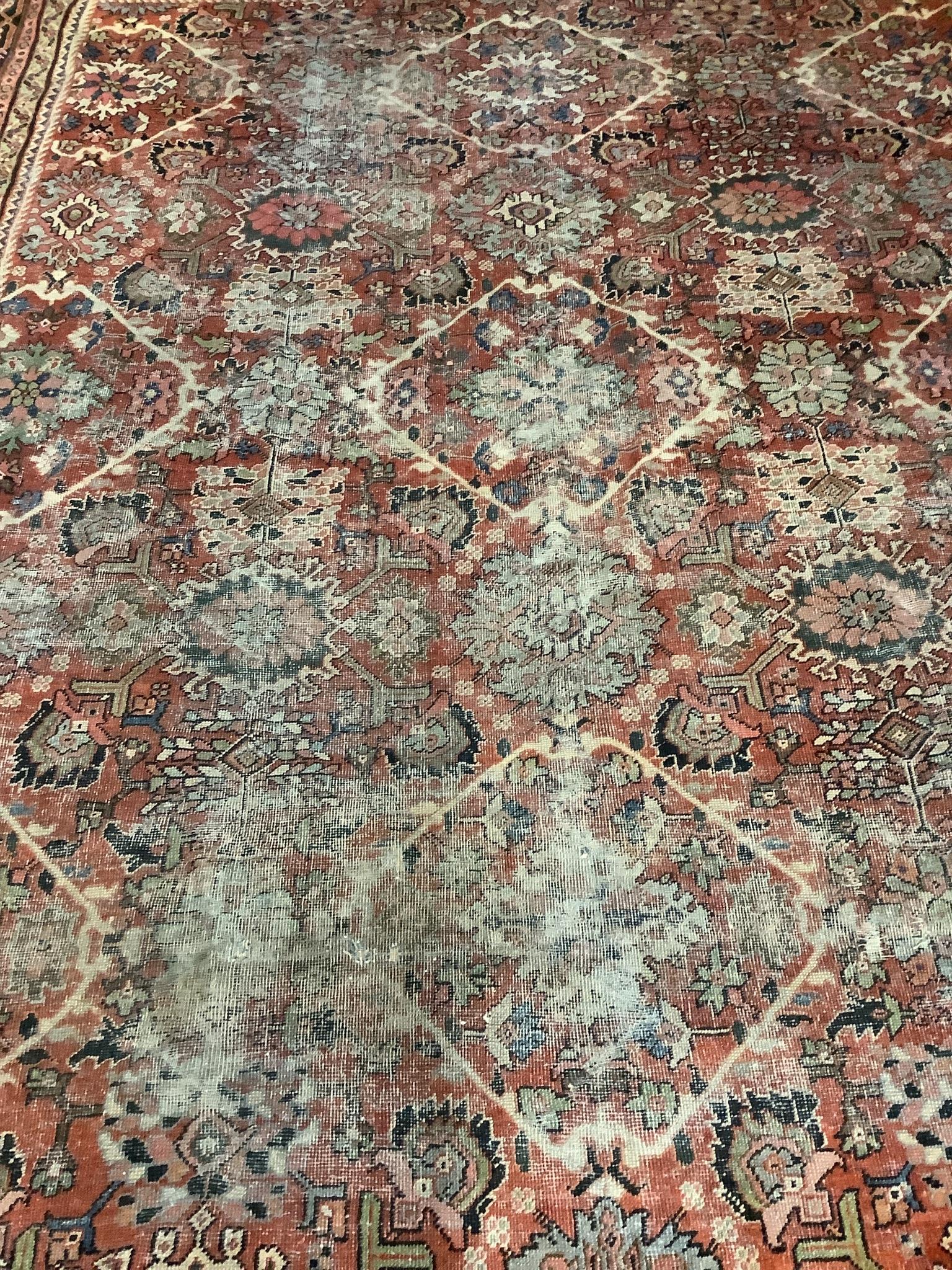 An early 20th century Heriz brick red ground carpet (worn), 418 x 330cm